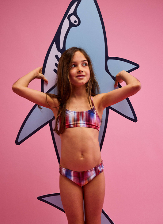 Una giovane ragazza indossa un bikini rosa per ragazze, con la stampa Ikat Flowers di Vilebrequin.