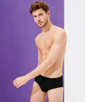 Bañador slip ajustado de color liso para hombre Negro vista frontal desgastada