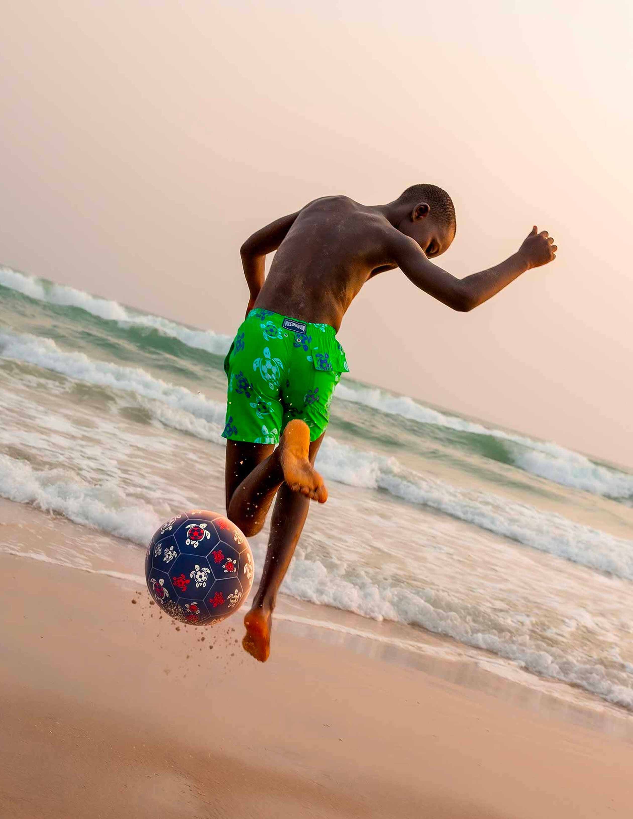 Soccer turtles Un niño jugando al fútbol en la playa