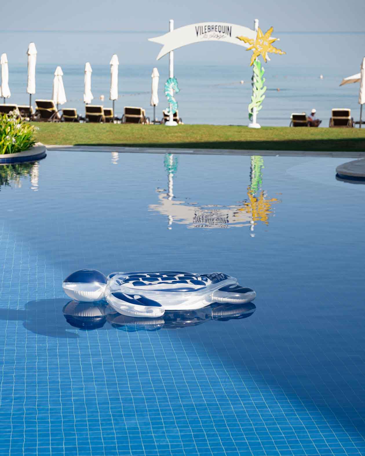 Une tortue gonflable flotttant dans une piscine face à la mer