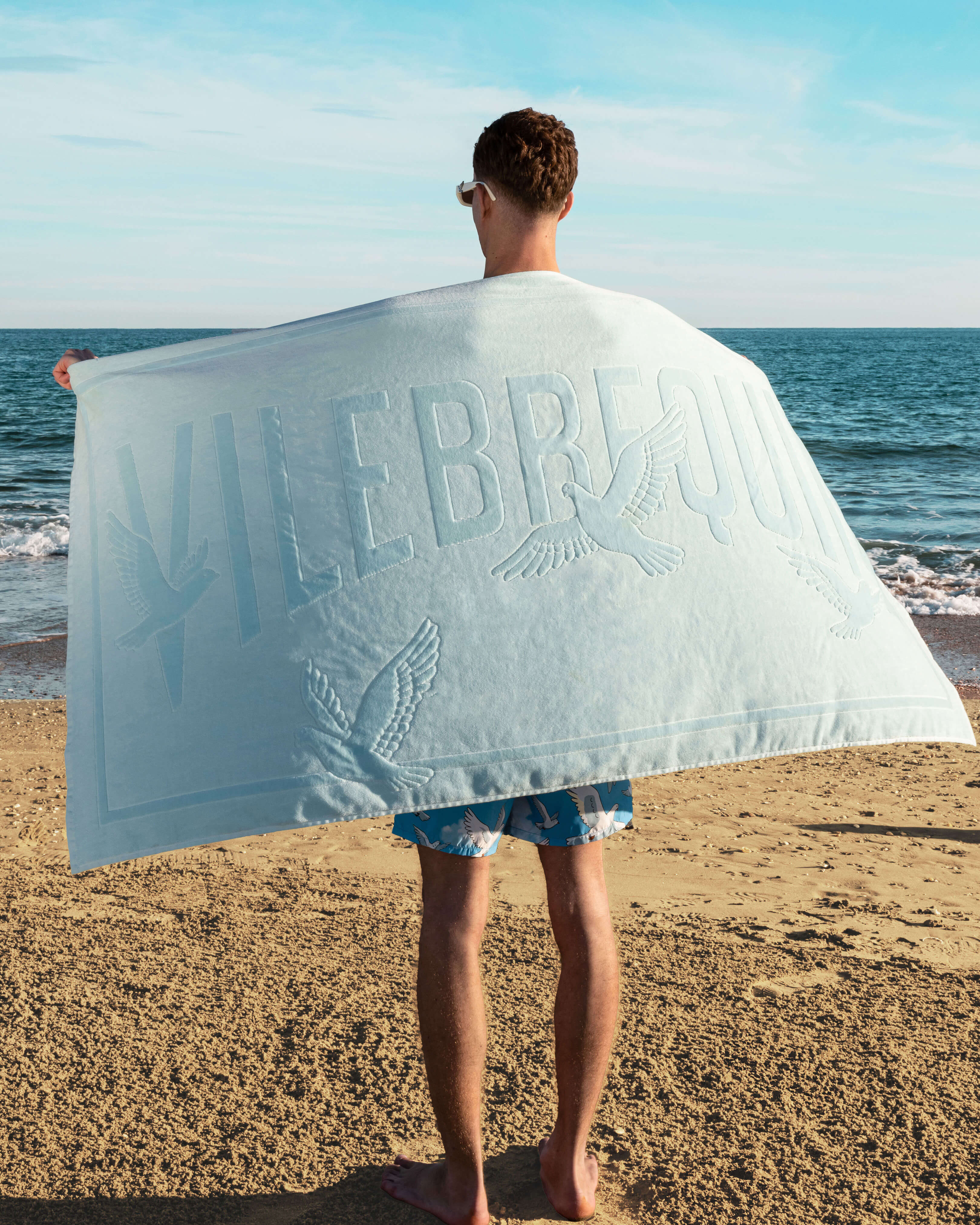 Toalla de playa de algodón orgánico con estampado Doves para hombre - VBQ x 3.PARADIS BLEU GIVRE lifestyle view