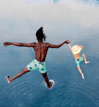 Father and Son jumping in pool wearing matching swimshorts