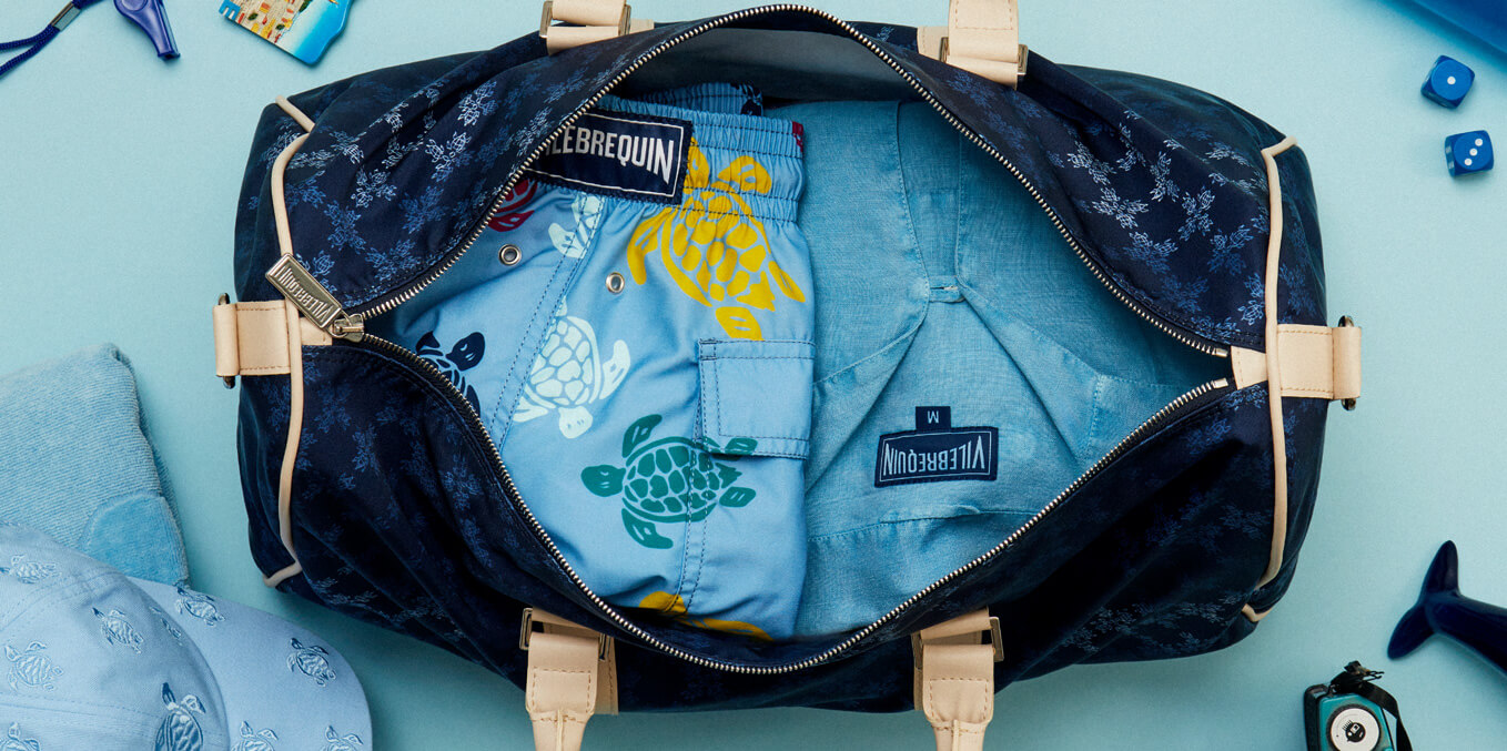 Blue swim shorts and blue linen shirt in a men’s travel bag