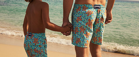 Father and son wearing matching swimsuits at the beach