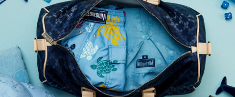 Blue swim shorts and blue linen shirt in a men’s travel bag