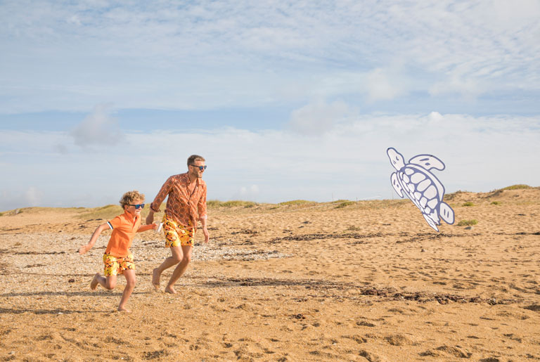 Father and son running on the beach with the Vilebrequin turtle kite
