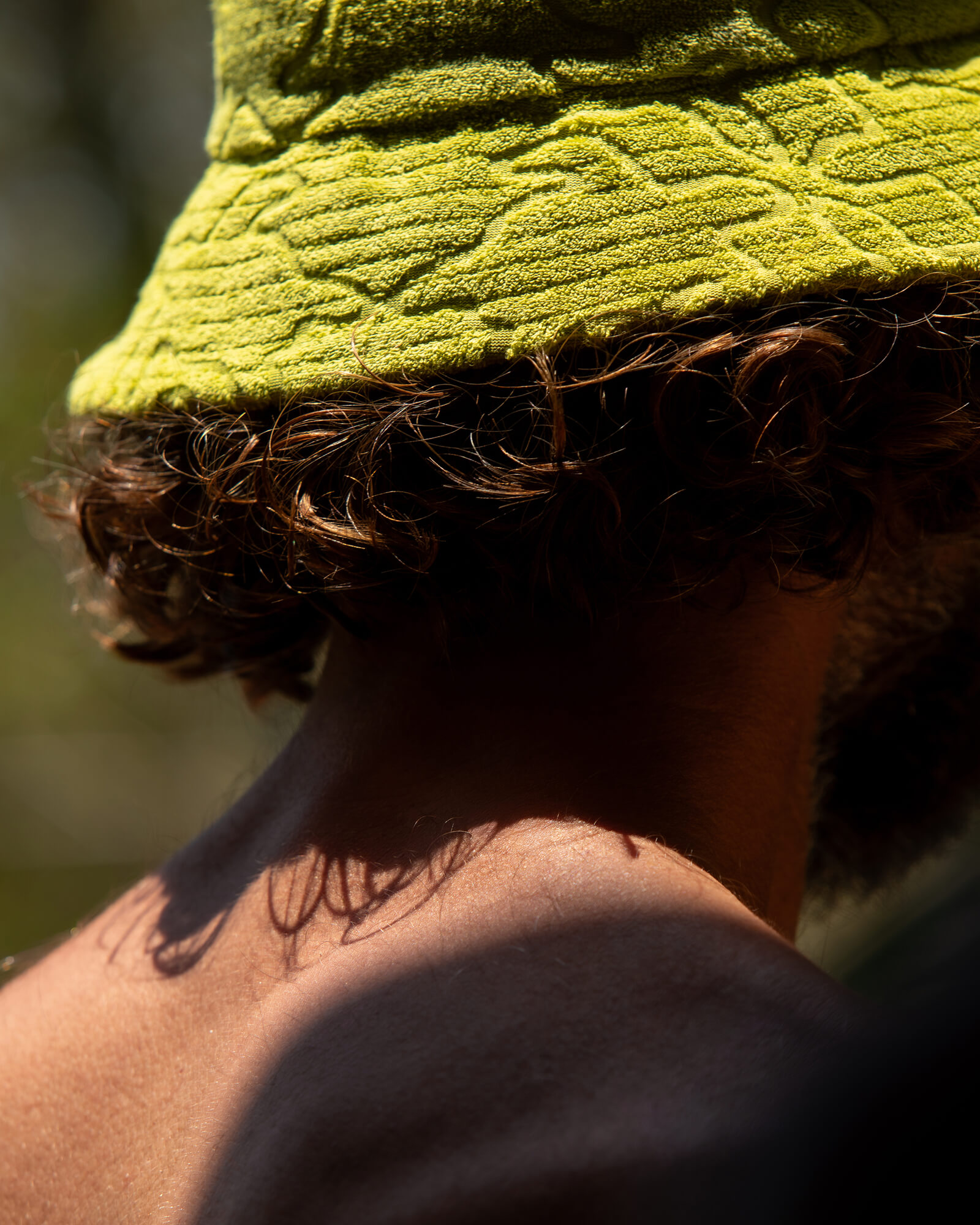 Vista posterior de primer plano de una persona con un gorro piluso de loungewear verde lima en tejido de rizo con patrón texturizado Gorro piluso de loungewear en tejido de rizo verde lima - Colección de accesorios de verano para hombre
