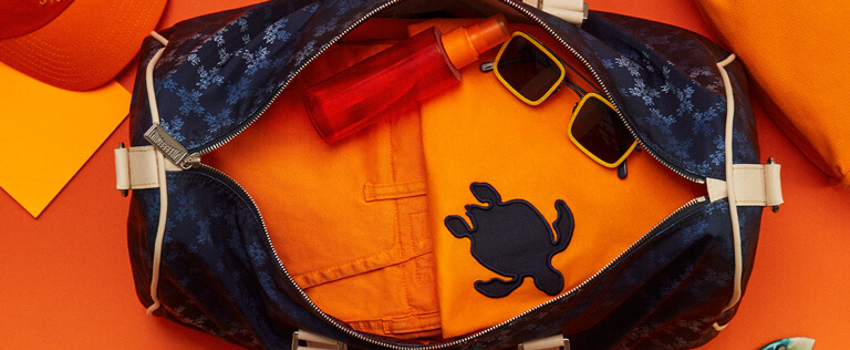 Orangefarbene Hose und Pullover in einer Reisetasche für Herren und Damen