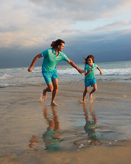 Man and kid on the beach wearing a blue swim shorts