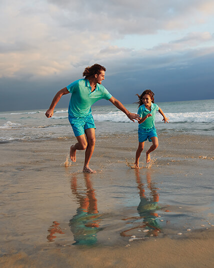 Homme et enfant sur la plage en maillot de bain bleu turquoise