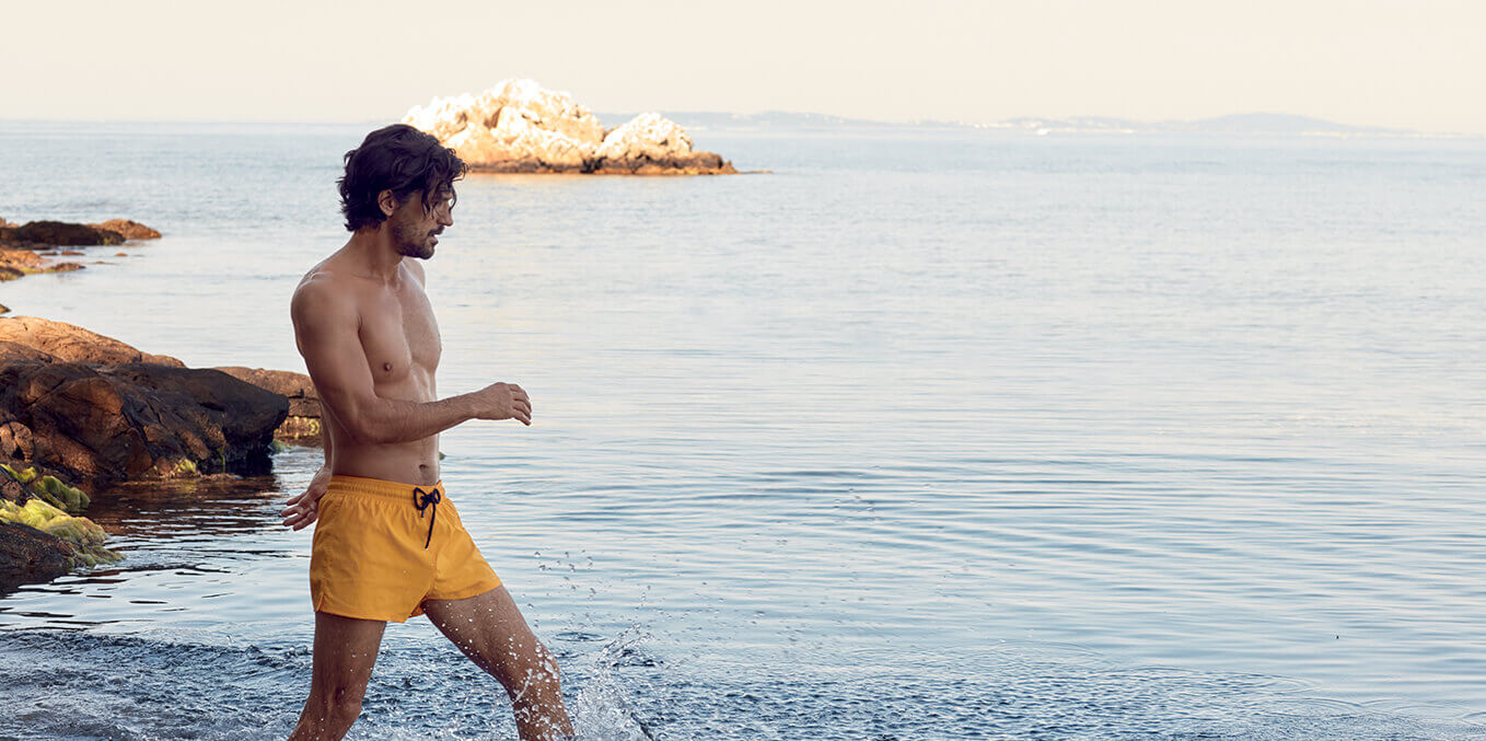 Man wearing a yellow short cut swim trunks