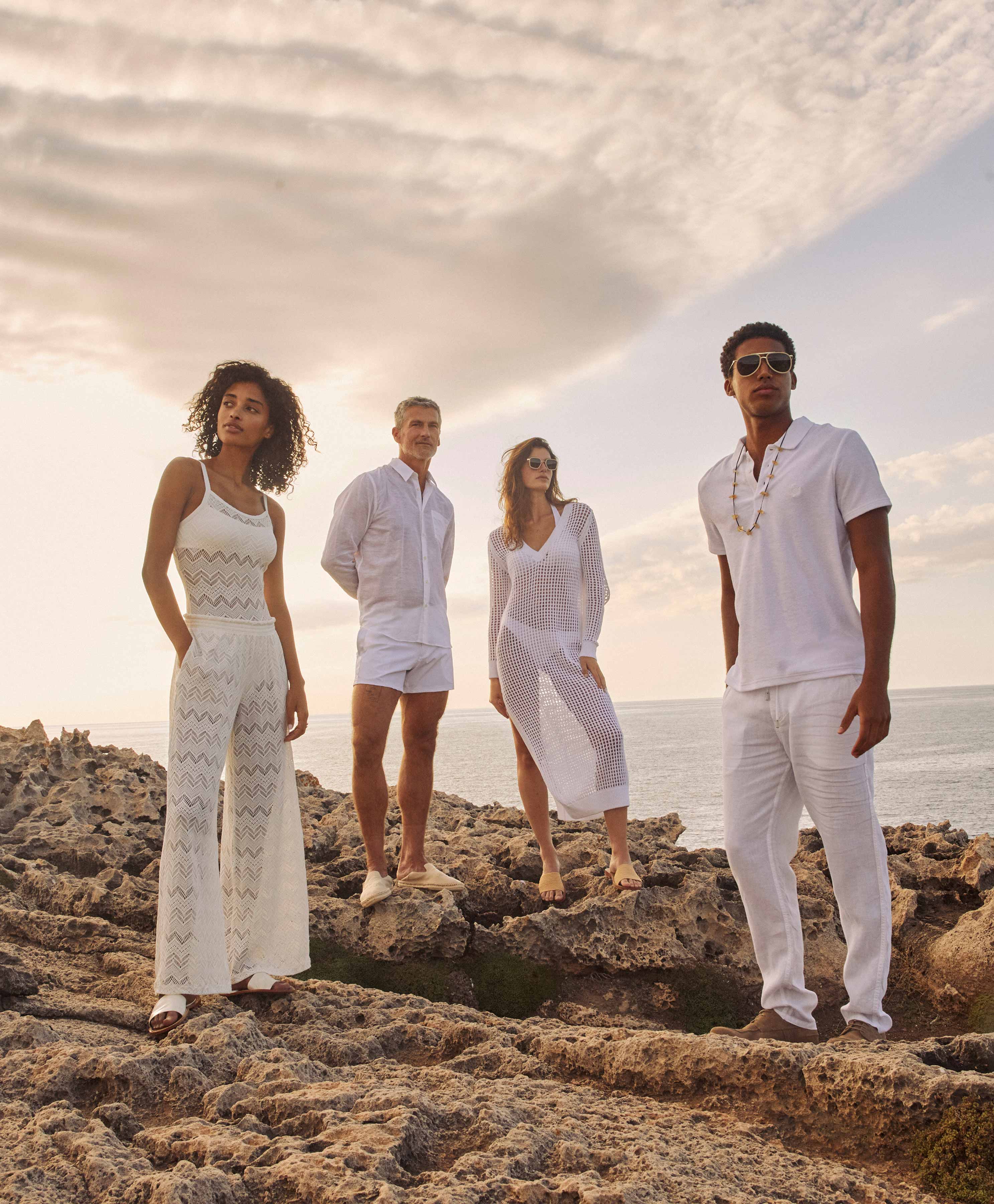 People on Rocks Four people dressed in white on coastal rocks.