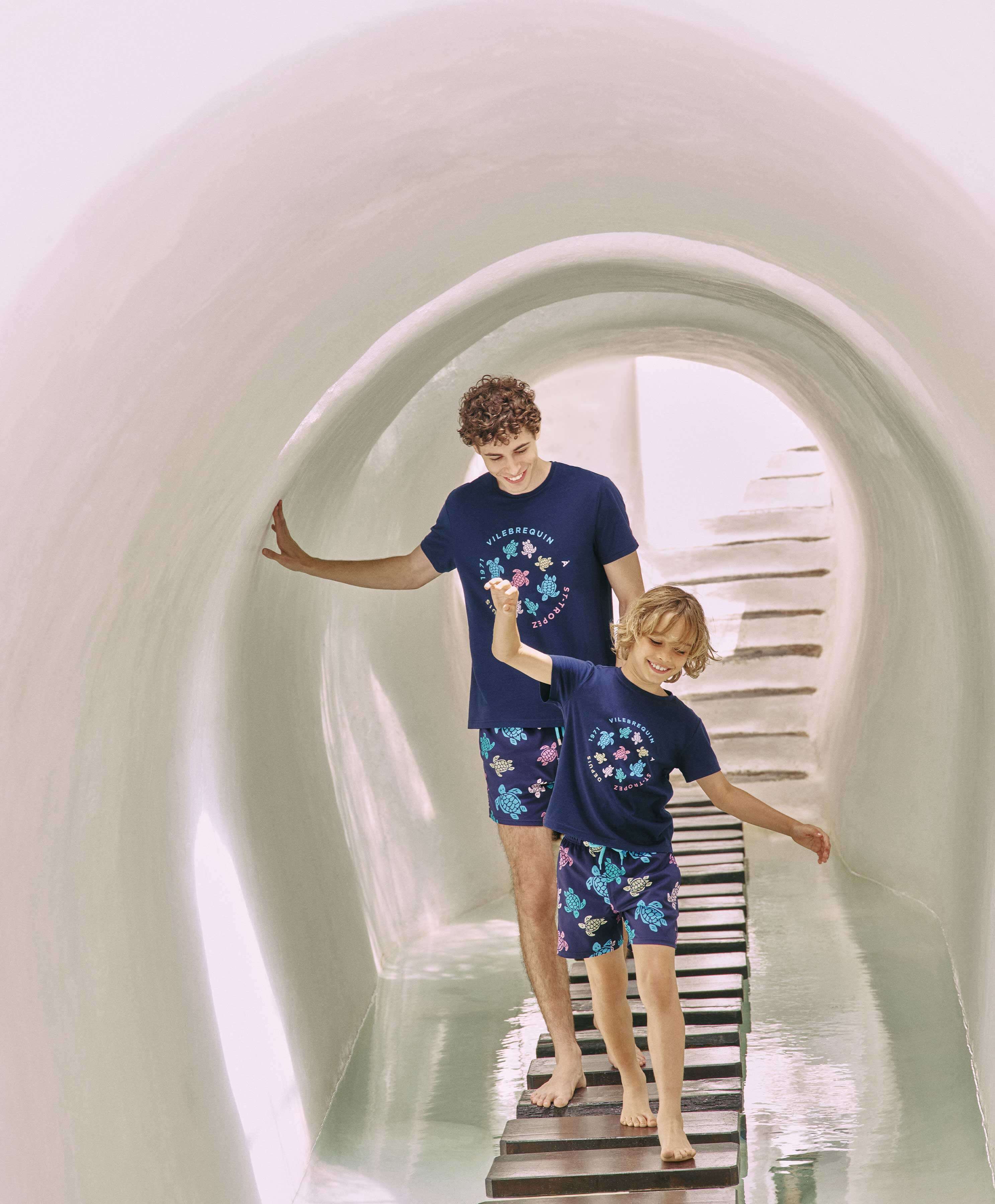 Father and son wearing matching blue swim trunks