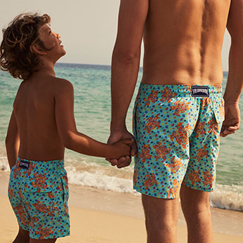 Father and son wearing matching swimsuits at the beach