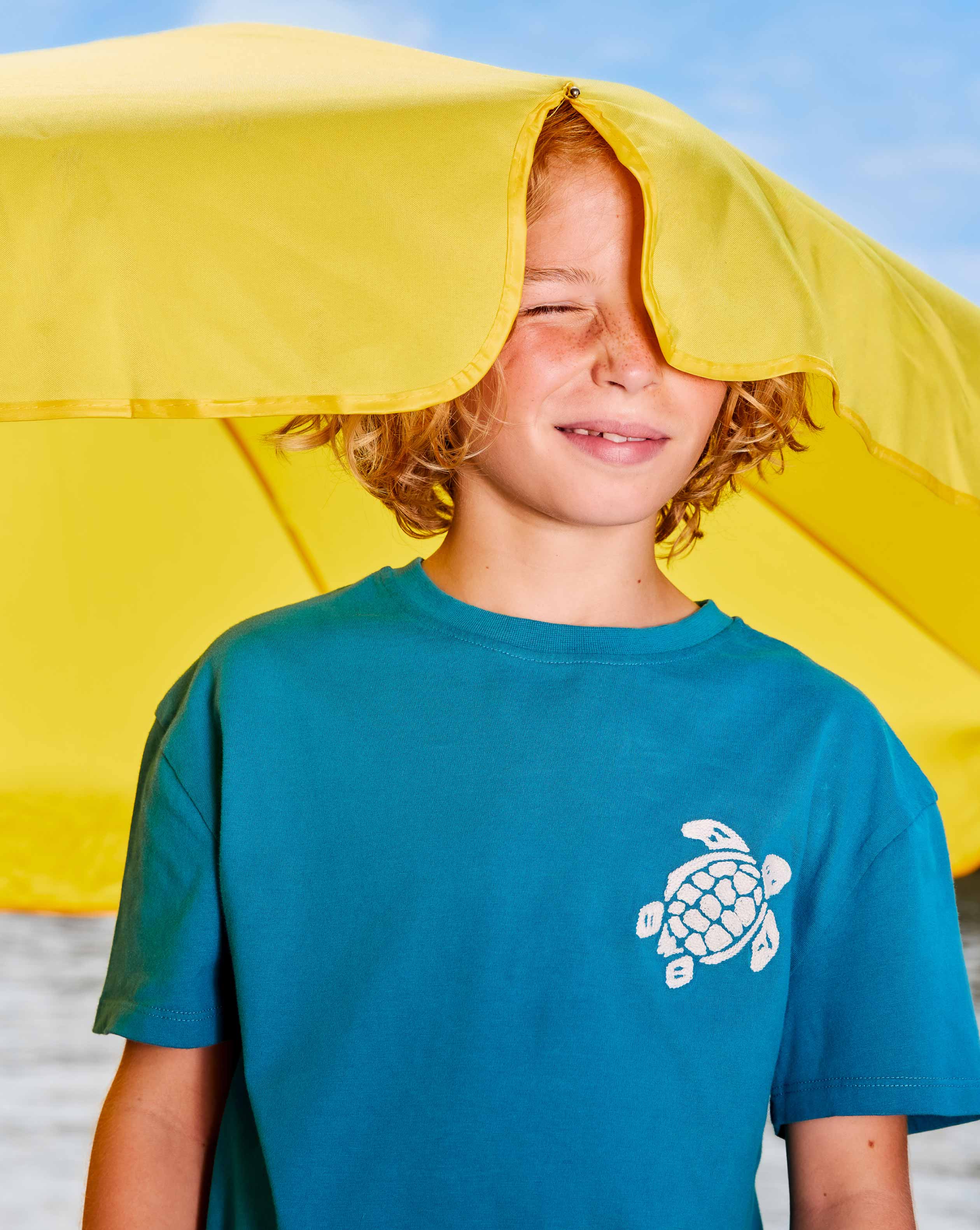 boy in pants in front of the sea