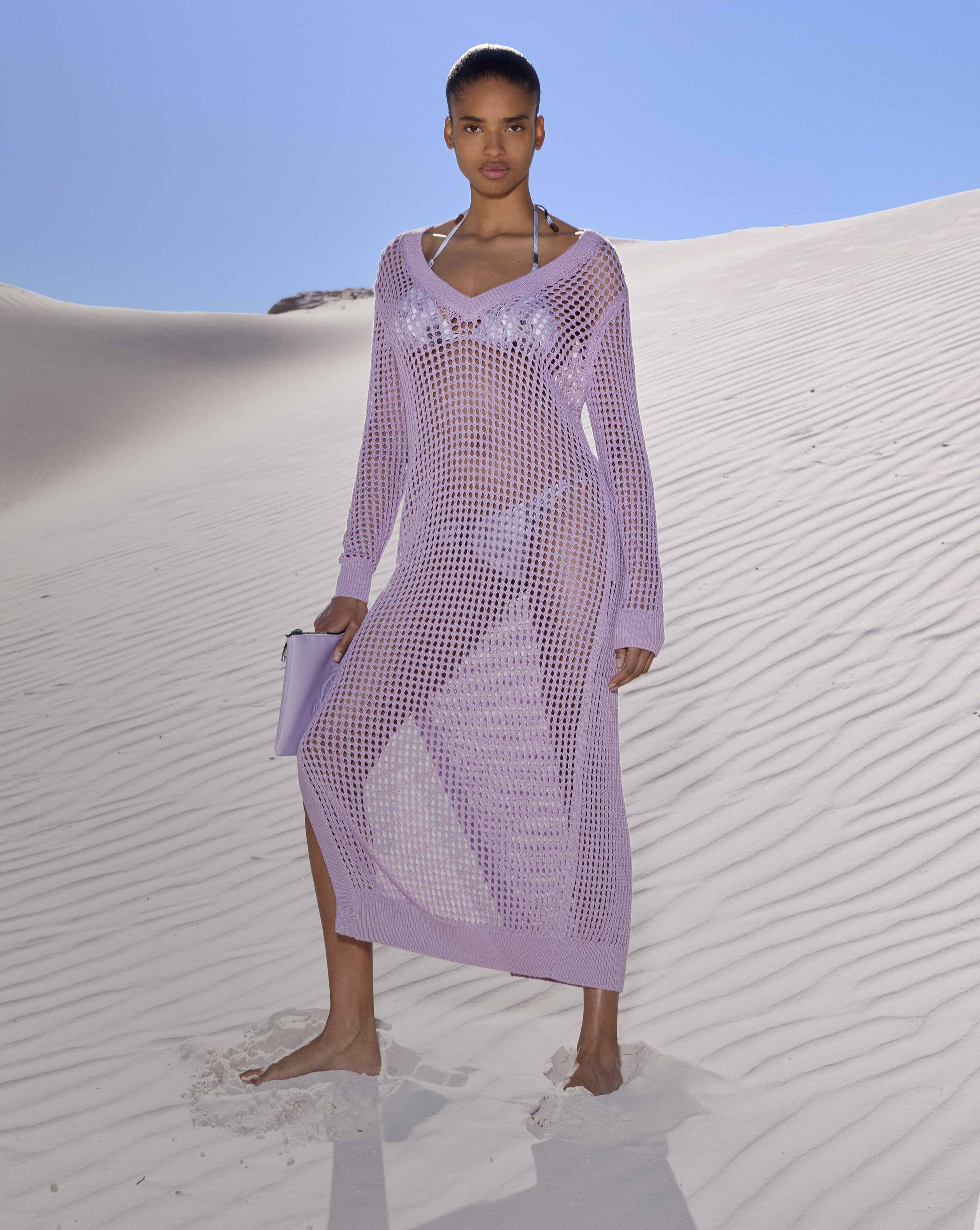 Une femme, habillée d'une robe noire, se tient devant la mer