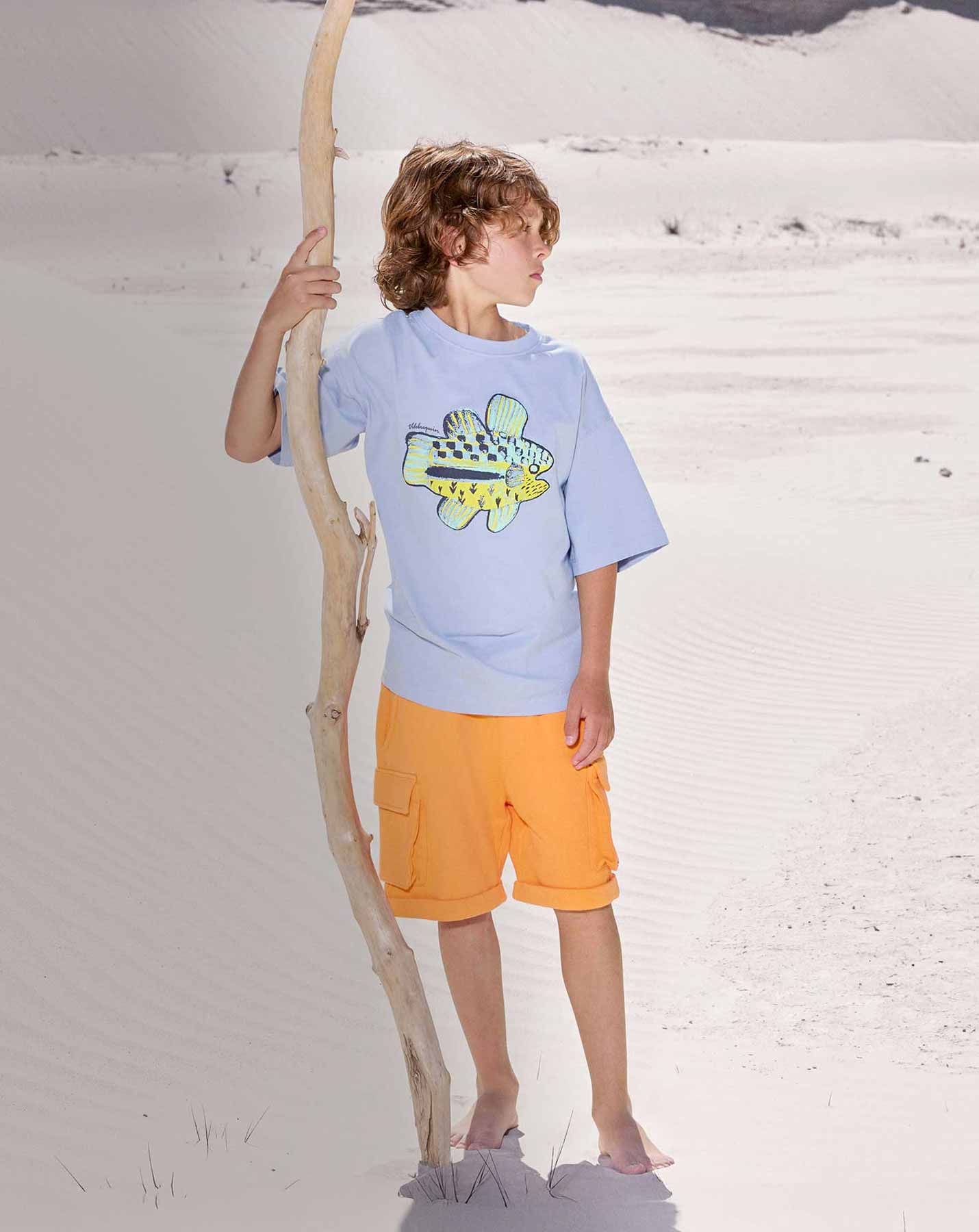 ragazzo al mare con pantaloncini da bagno, camicia e occhiali da sole